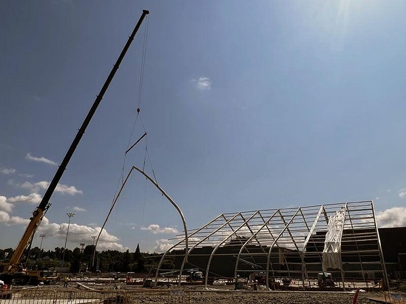 a crane is lifting a large frame piece from a structure of pipes