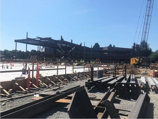 a steel frame is being built on top of a concrete floor. a crane is on the left side