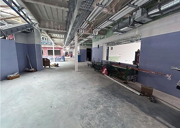 a hallway under construction has utility runs in ceiling and wall board being placed on walls